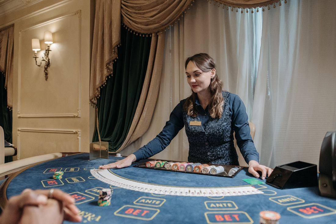 Dealer membagikan kartu dan menyusun chip di meja permainan